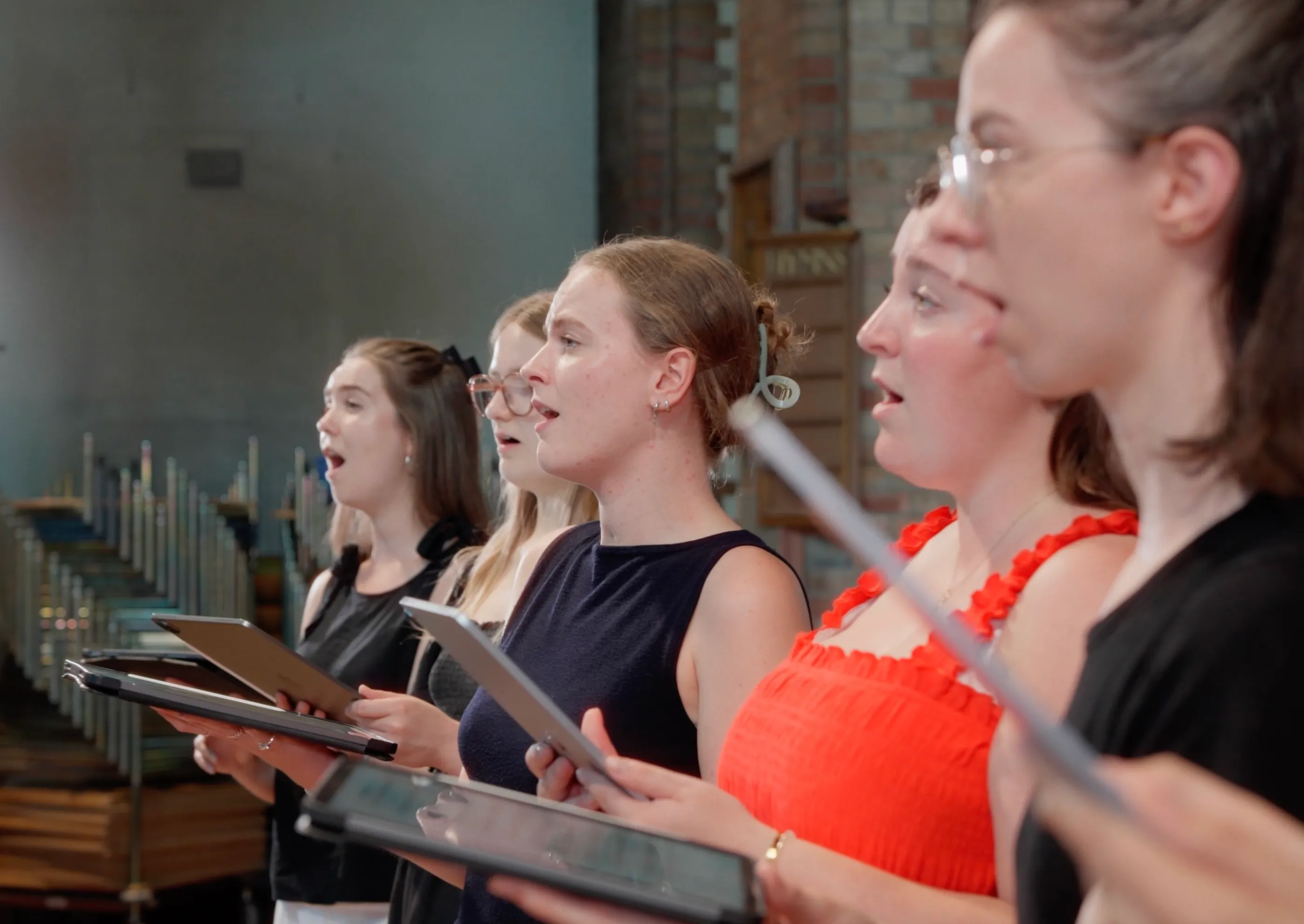 Five Alma Consort singers performing from iPads during a recording session in a London church.